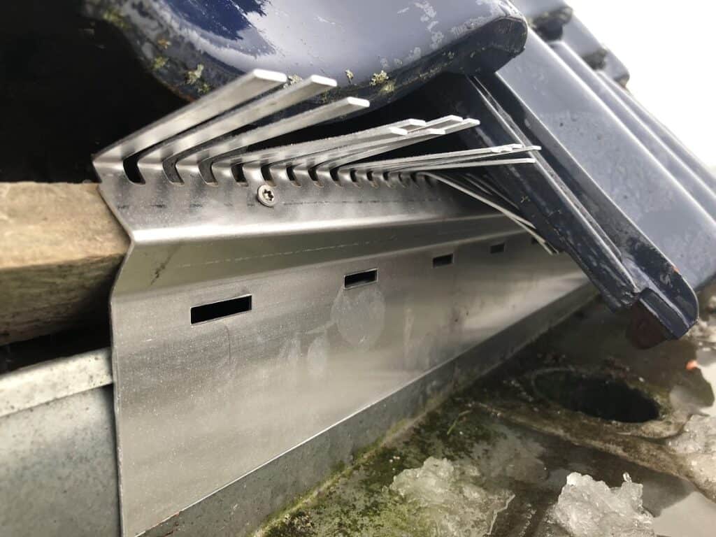 Dakvoetprofiel met geïntegreerde vogelwering pinnen onder dakpannen, close-up.